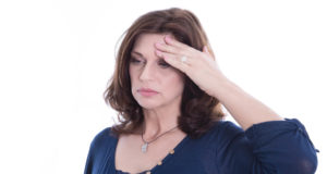 Mulher com dor de cabeça, um dos sintomas da menopausa